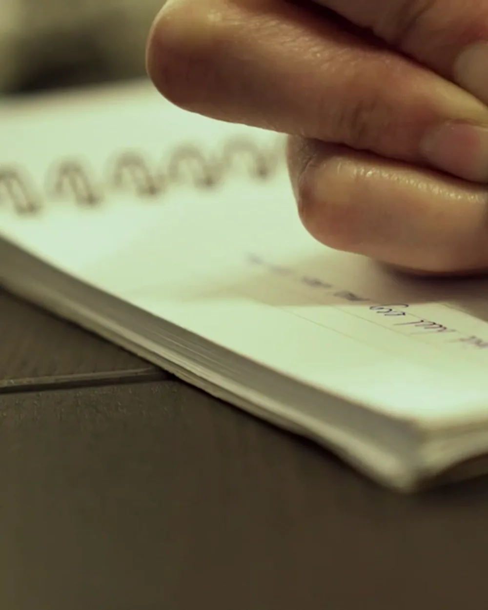 Una mano anotando sobre un cuaderno, en primer plano.